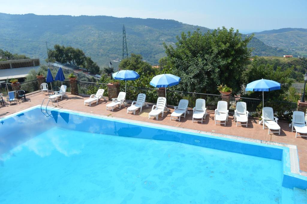 a swimming pool with lounge chairs and umbrellas at Il Falco del Cilento in Torchiara