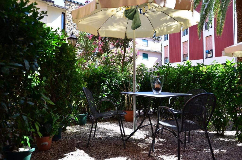 a table and chairs under an umbrella in a garden at Verdeacqua in Monterosso al Mare