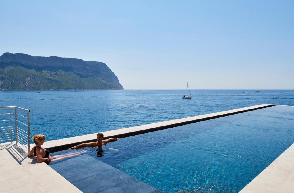 two children in a swimming pool overlooking the water at Hôtel Les Roches Blanches Cassis in Cassis