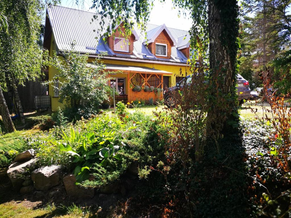 una casa amarilla con un jardín delante de ella en Agrowczasy u Mirusi, en Wiżajny