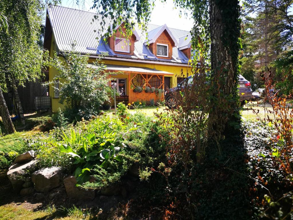 una casa gialla con un giardino di fronte di Agrowczasy u Mirusi a Wiżajny