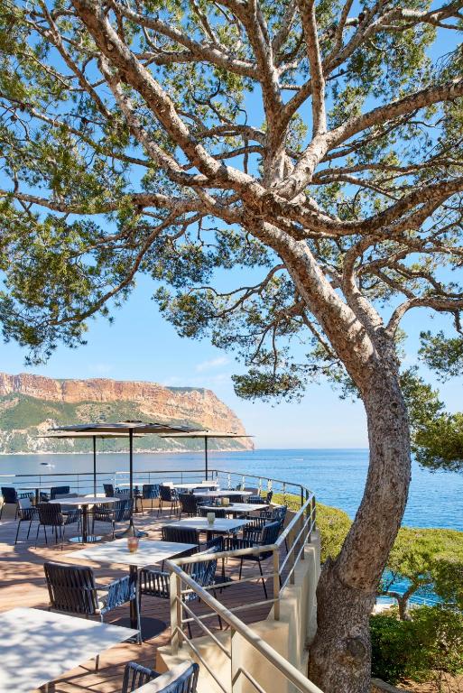 a restaurant with tables and chairs next to the ocean at Hôtel Les Roches Blanches Cassis in Cassis