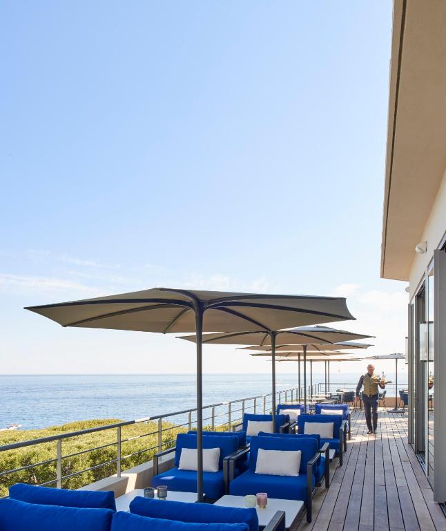 a row of blue chairs and umbrellas on the beach at Hôtel Les Roches Blanches Cassis in Cassis