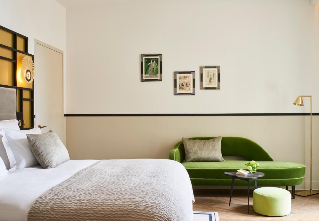 a bedroom with a bed and a green couch at Hôtel Les Roches Blanches Cassis in Cassis