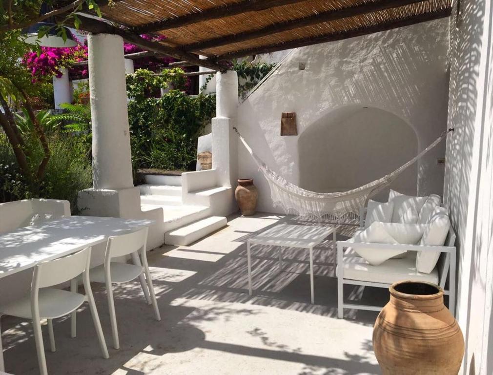 un patio con sillas blancas, mesa, mesa y sillas en La Porta Rossa, en Stromboli