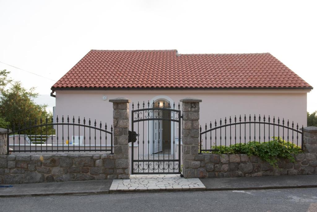 een wit huis met een poort en een stenen muur bij Villa Mara Smokvica Krmpotska in Klenovica