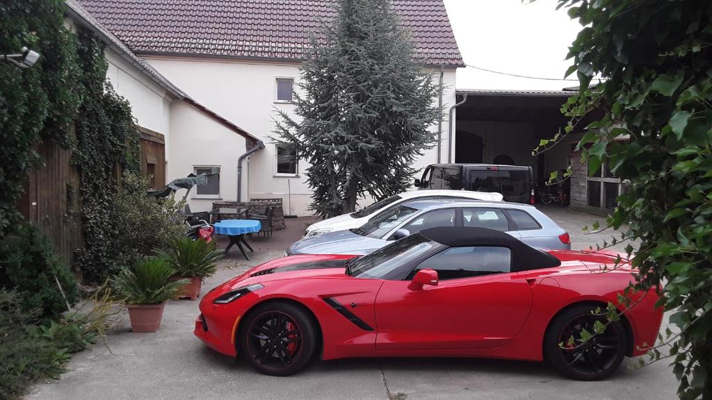 a red car parked next to two cars in a driveway at Gästezimmer Sommer Locktow in Locktow
