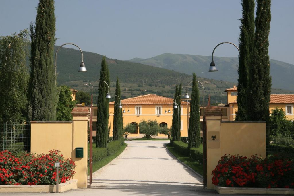 uma entrada que leva a uma casa com árvores e flores em Delfina Palace Hotel em Foligno