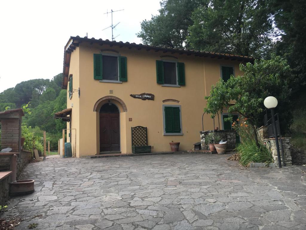 Casa amarilla con persianas verdes y entrada en Villa Corinna, en Greve in Chianti