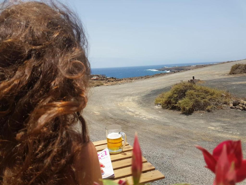 Kobieta siedząca na stole ze szklanką piwa w obiekcie Los Ancones Apartment w Costa Teguise