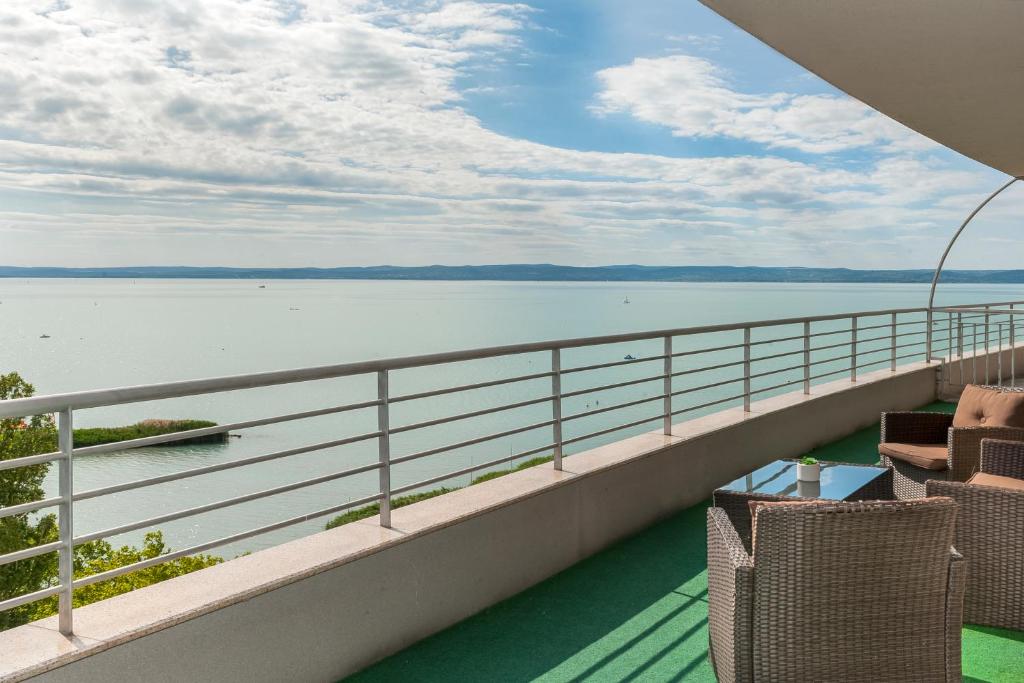 balcón con sillas y vistas al agua en MF Club 218 Palazzo Wellness Apartment en Siófok
