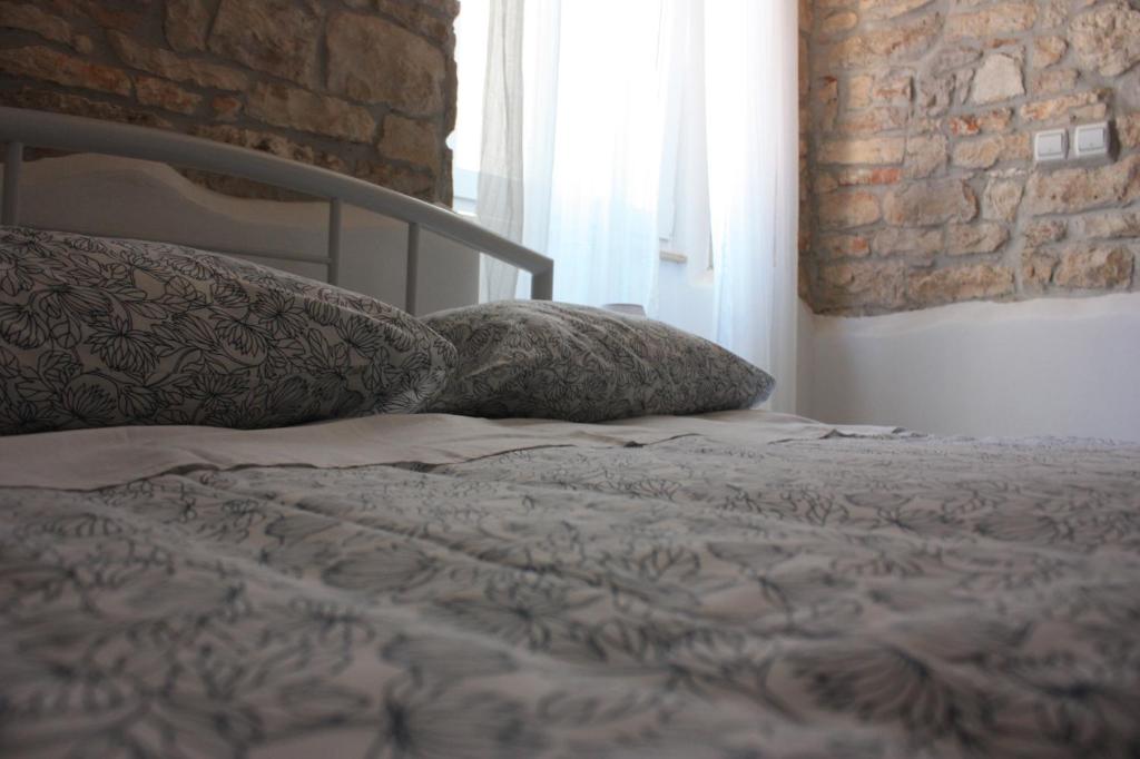 łóżko z 2 poduszkami i ceglaną ścianą w obiekcie Villa Piazza grande w Fažanie