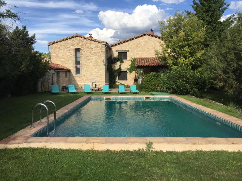 a pool in front of a house with blue chairs at Casa de las Hazas in Poyatos