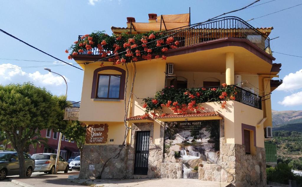 a yellow building with flower boxes on it at Hostal Yuste in Garganta la Olla