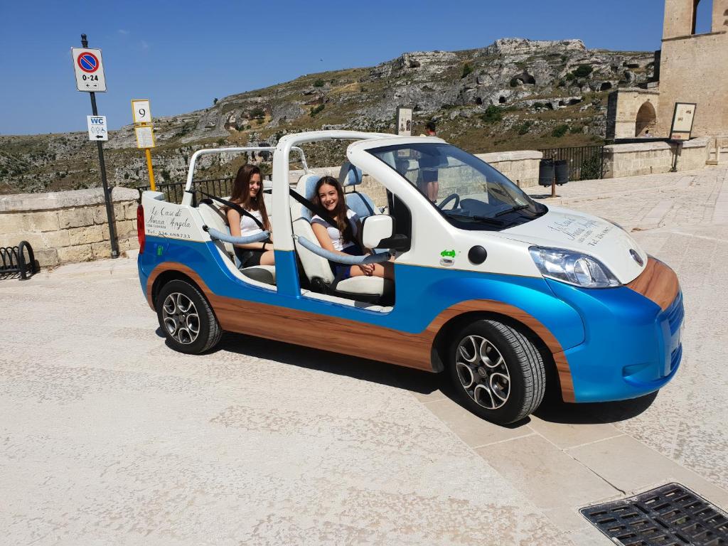 Deux femmes dans une petite voiture électrique dans l'établissement Le Case Di Nonna Angela, à Matera