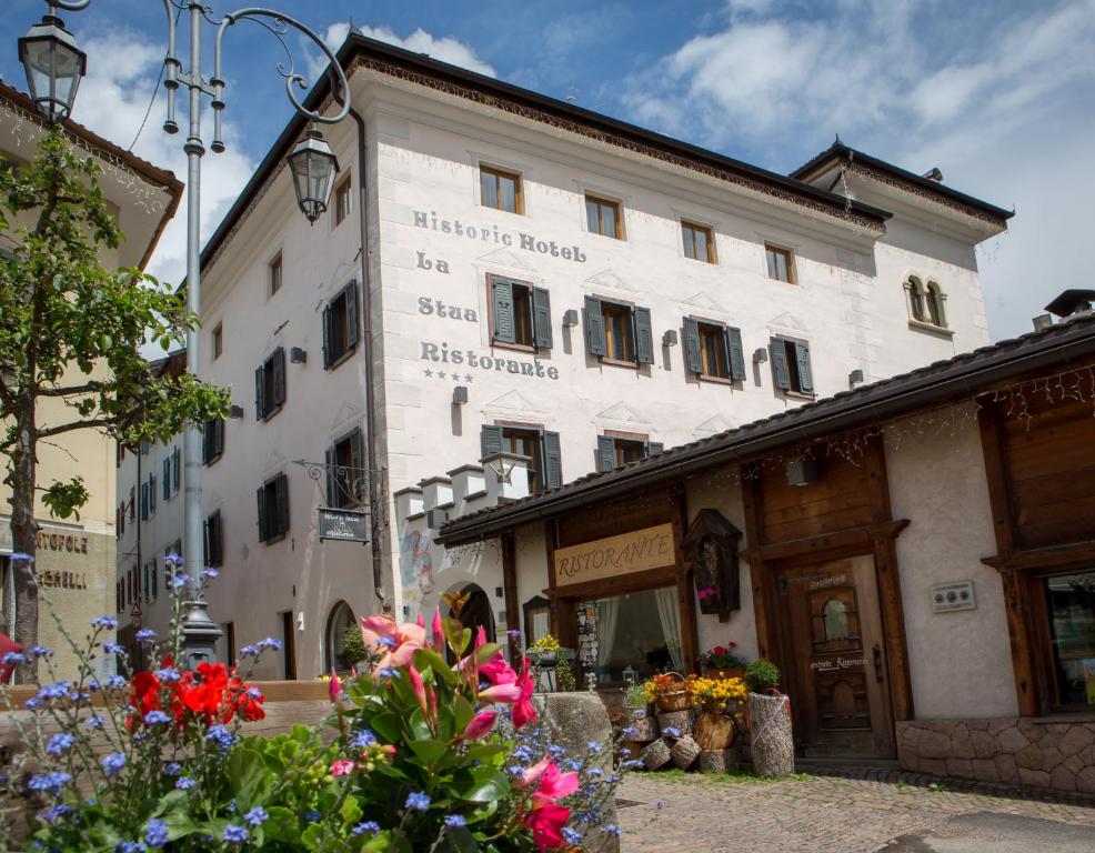 a large white building with flowers in front of it at Historic Hotel Ristorante La Stua in Cavalese