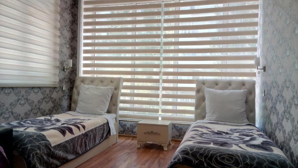 two beds in a room with a window with blinds at Sheki Guest House in Sheki