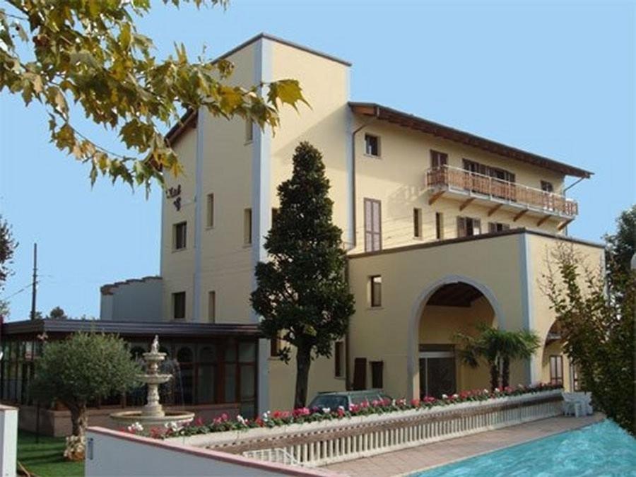 ein großes Gebäude mit einem davor geparkt in der Unterkunft Hotel Magnolia in Comacchio