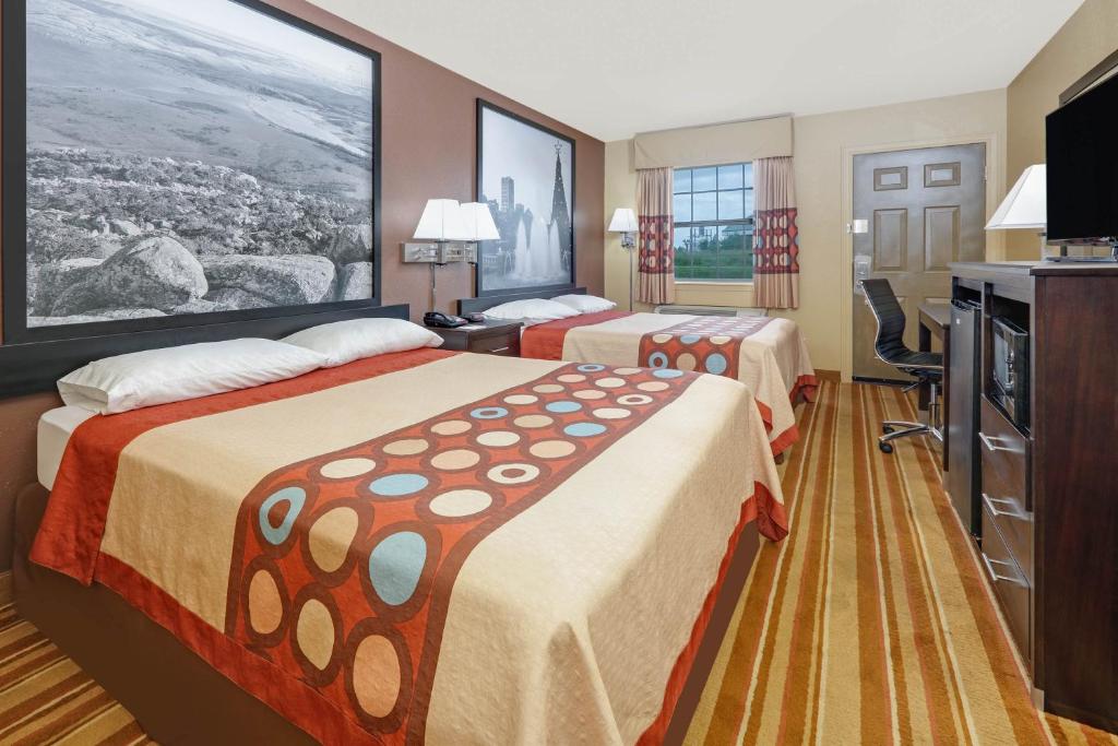 a hotel room with two beds and a flat screen tv at Super 8 by Wyndham Big Cabin/Vinita Area in Vinita