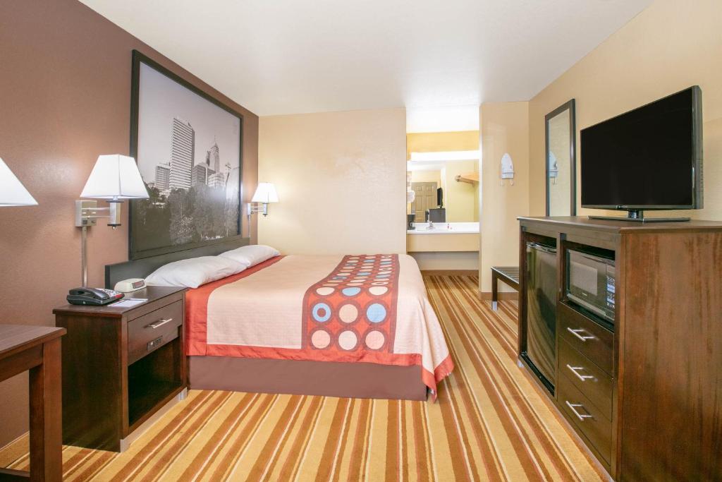 a hotel room with a bed and a flat screen tv at Super 8 by Wyndham Big Cabin/Vinita Area in Vinita