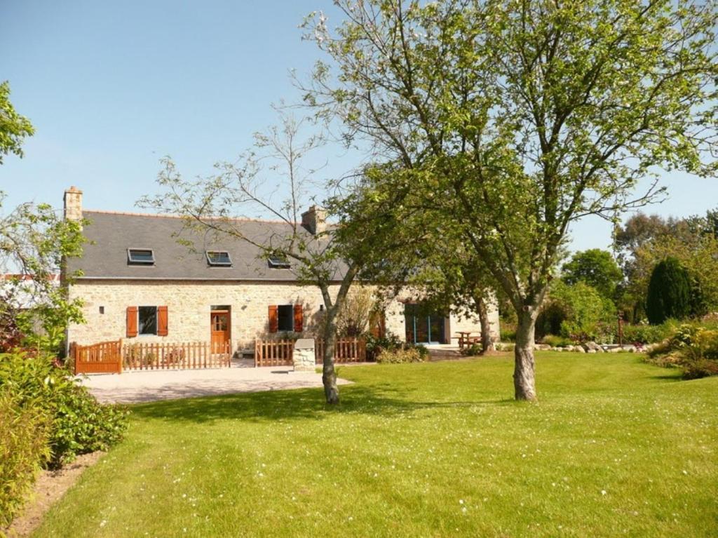 a stone house with two trees in the yard at La Ferme du Père in Kermorocʼh