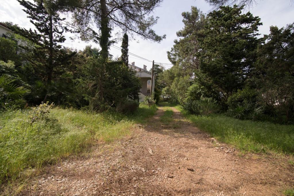 a dirt road in front of a house with trees at Apartment in Veli Losinj 34691 in Veli Lošinj