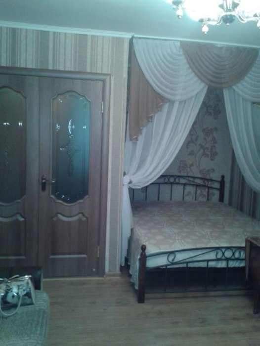 マリウポリにあるКвартира с видом на мореのベッドルーム1室(ベッド1台付)、カーテン付きのドアが備わります。