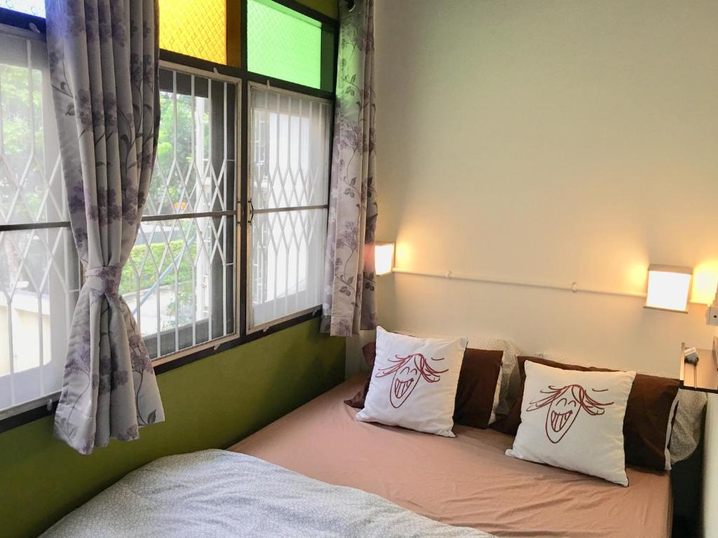 a bedroom with a bed with two windows at Bangkok Sanookdee Hostel in Bangkok