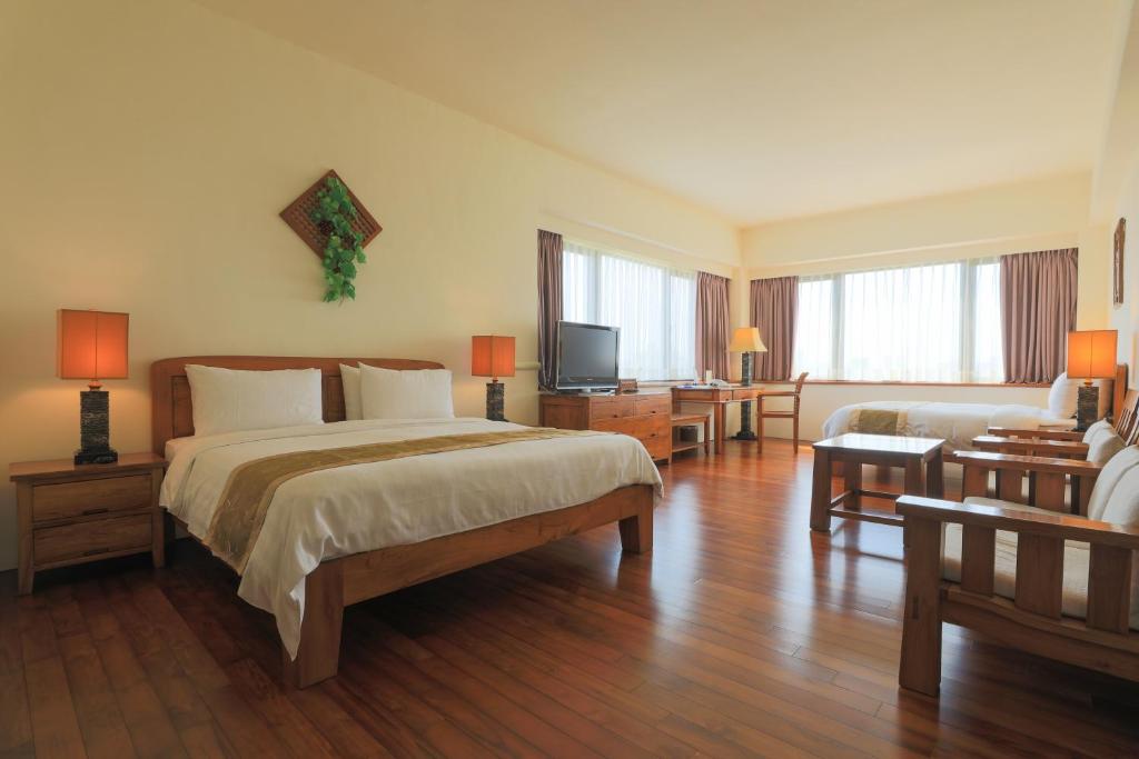 ein Schlafzimmer mit einem Bett, einem Sofa und einem TV in der Unterkunft Yentai Hotel in Magong
