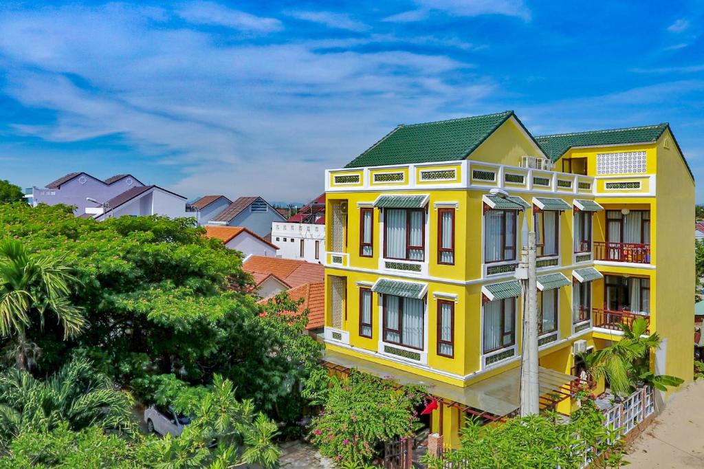 une maison jaune avec un toit vert dans l'établissement Hoi An Corner Homestay, à Hội An