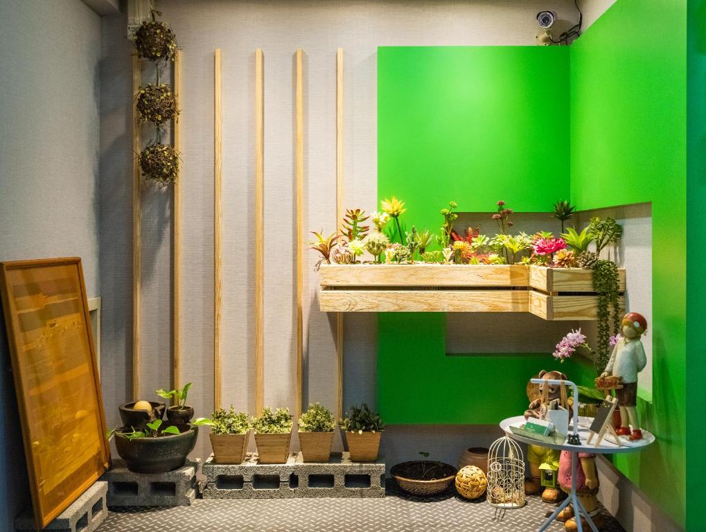 ein Zimmer mit einer grünen Wand mit Topfpflanzen in der Unterkunft Gwawa Hotel in Kaohsiung