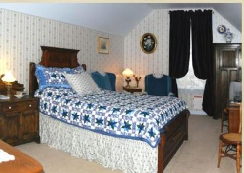 a bedroom with a large bed with blue and white sheets at B Street House Inn in Virginia City