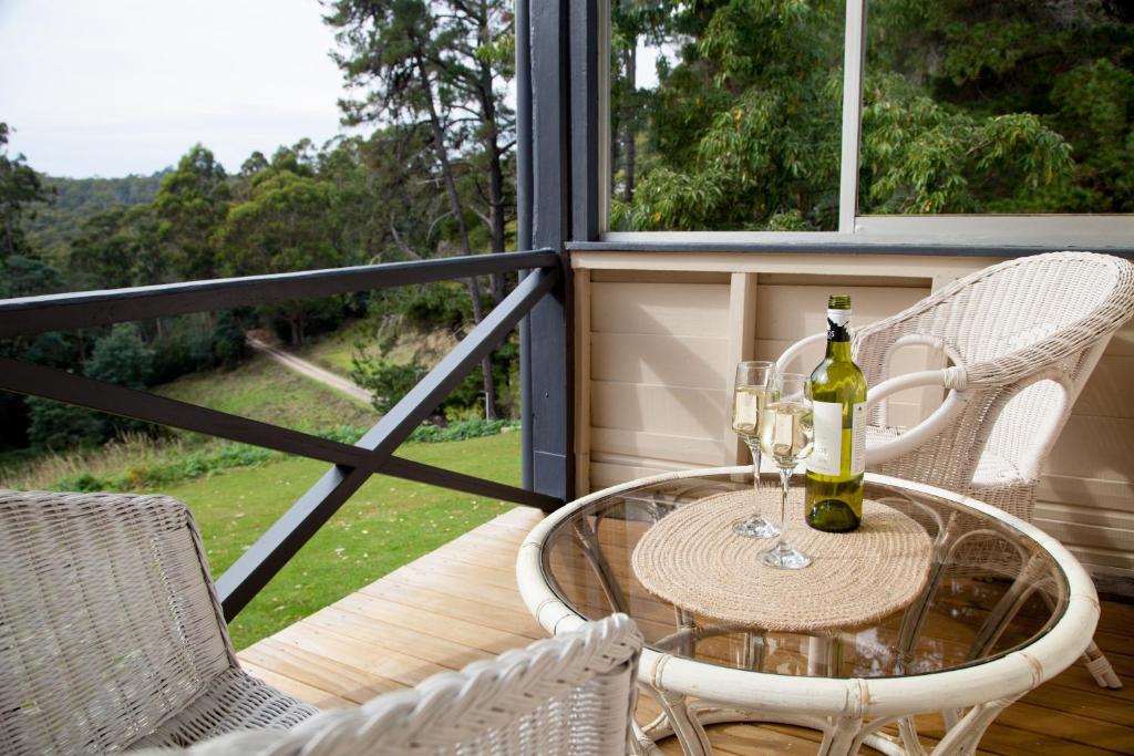 een tafel met een fles wijn en stoelen op een veranda bij The Pear Cottage in Nubeena