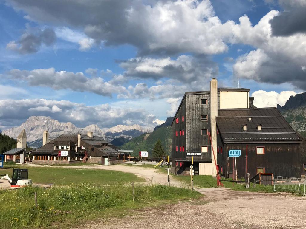 a group of buildings in a field with mountains at Piccolo Nido Falcade in Falcade