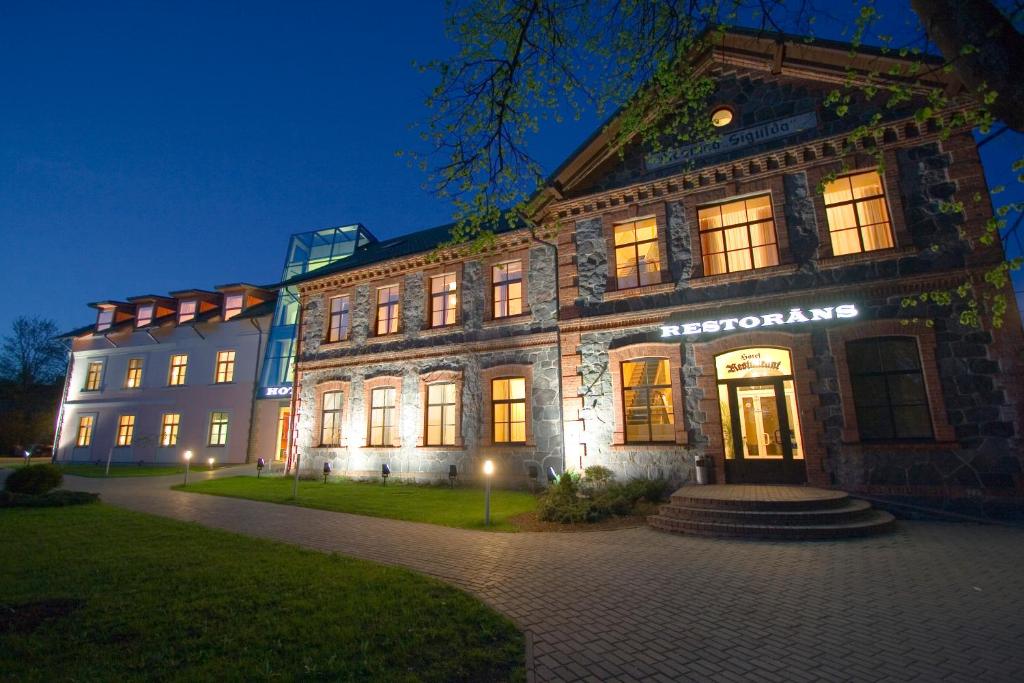 un gran edificio de ladrillo con un cartel en él por la noche en Hotel Sigulda, en Sigulda