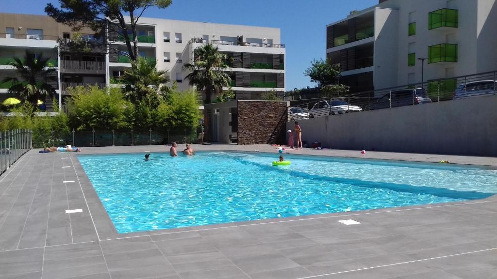- une piscine avec des personnes à l'eau dans l'établissement Appartement Le Parc Saint Raphaël, à Saint-Raphaël