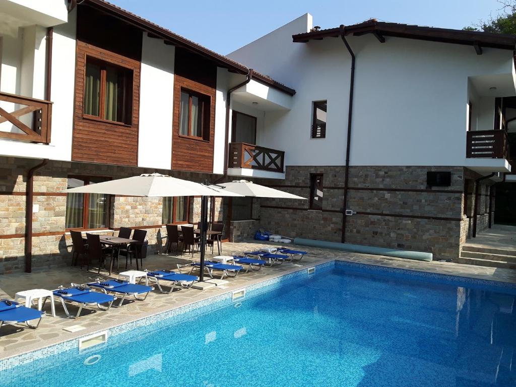 a swimming pool with chairs and umbrellas next to a building at Relax Houses in Ognyanovo