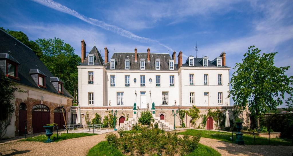 un grand bâtiment blanc avec un toit dans l'établissement Château du Jard, à Chaumont-en-Vexin