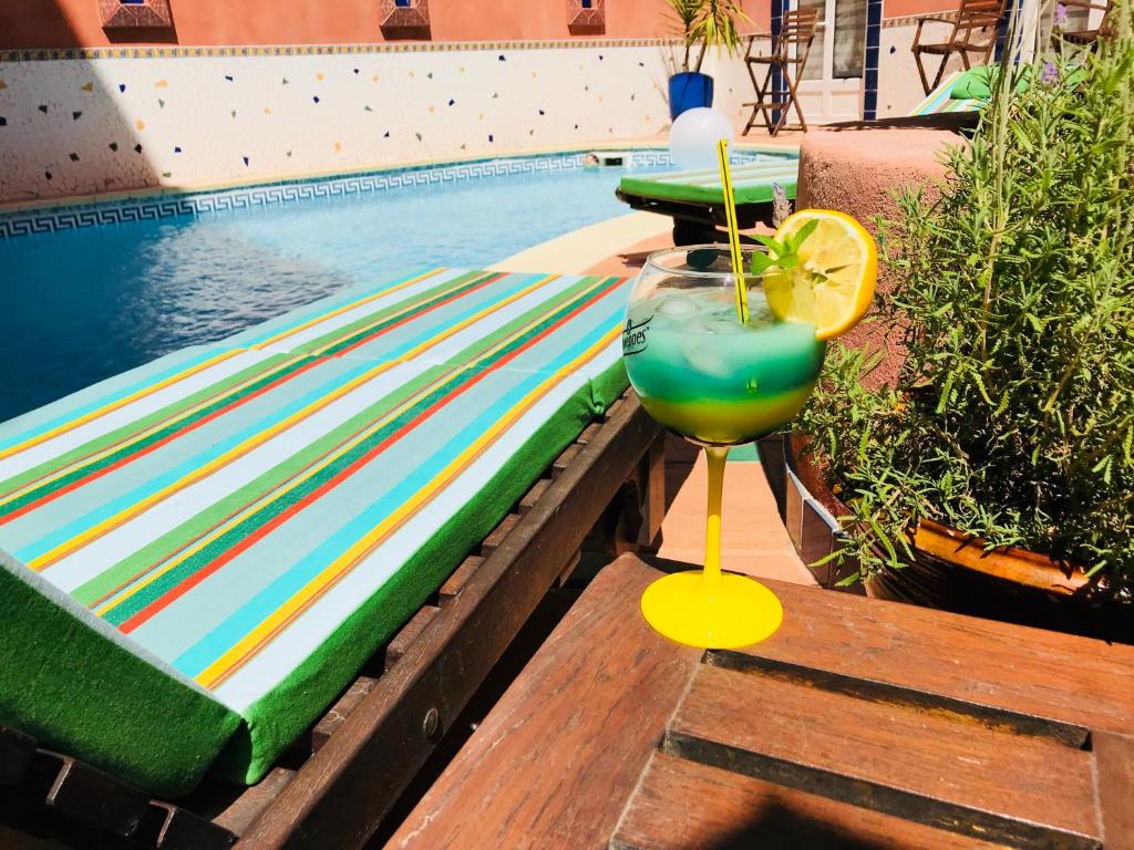 a drink sitting on a table next to a swimming pool at Logis Hôtel Restaurant de la Paix in Lodève