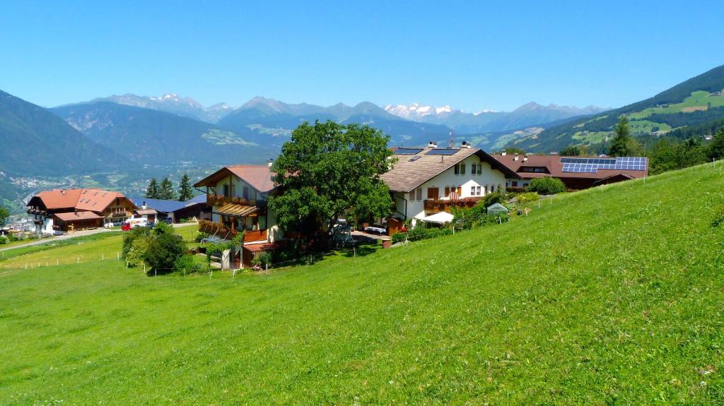 un grupo de casas en una colina verde con montañas en Pension Summererhof, en Bresanona