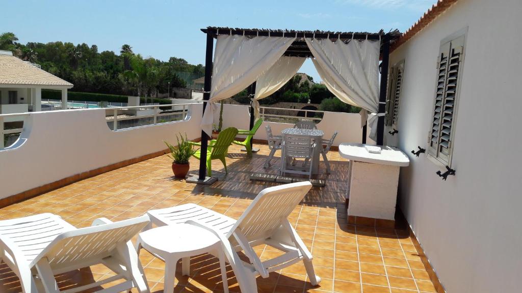 a patio with white chairs and a table on a balcony at Casa di Caucana in Santa Croce Camerina