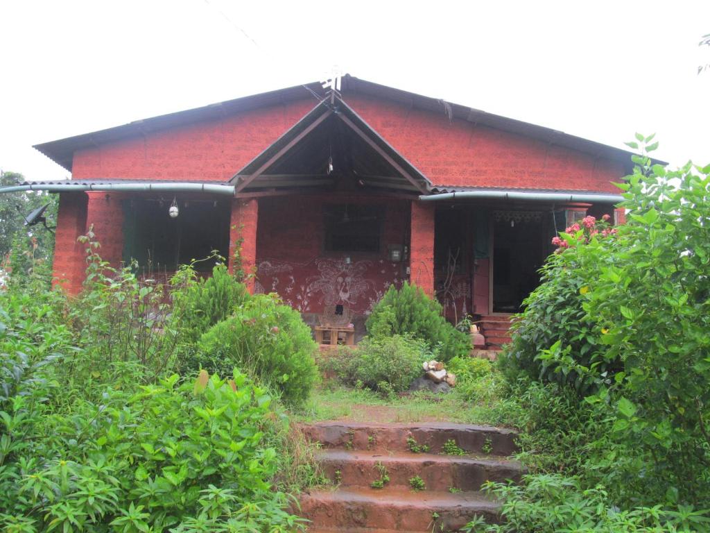 a red brick house with stairs in front of it at Vidya Konkan Agro Tourism in Chiplun