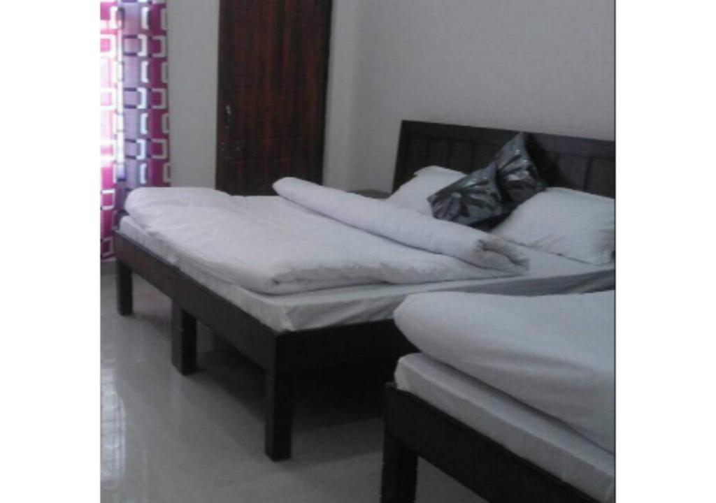 two beds in a room with white sheets and pillows at Ishwari Narayani Hotel in Joshīmath