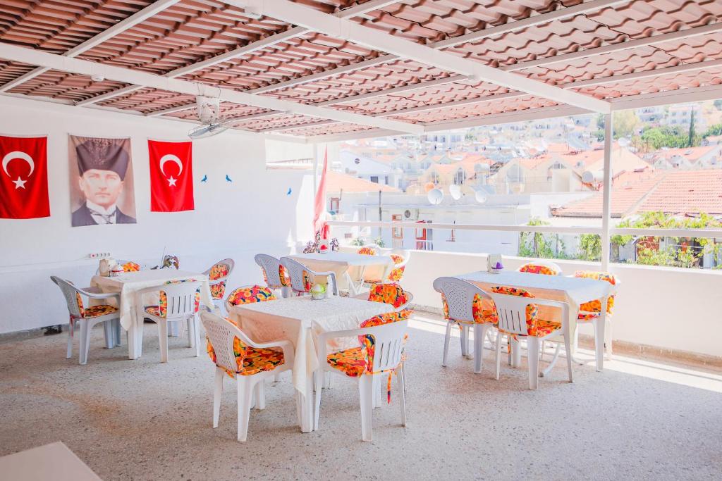 ein Esszimmer mit weißen Tischen, Stühlen und Flaggen in der Unterkunft Saray Hotel in Kaş