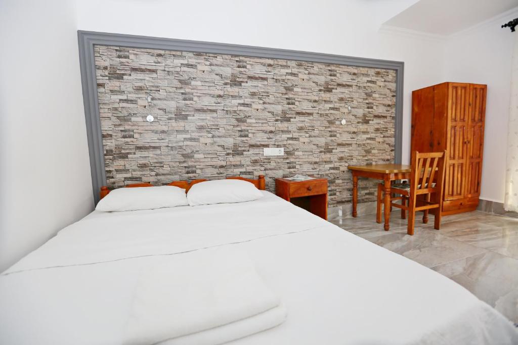 1 dormitorio con cama blanca y pared de ladrillo en Sulo Pension, en Patara