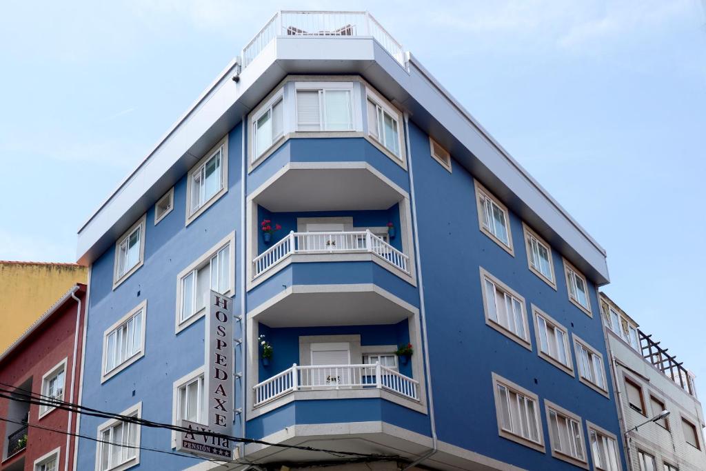 un edificio azul con ventanas y balcones blancos en Hospedaxe A Vila, en Pobra do Caramiñal