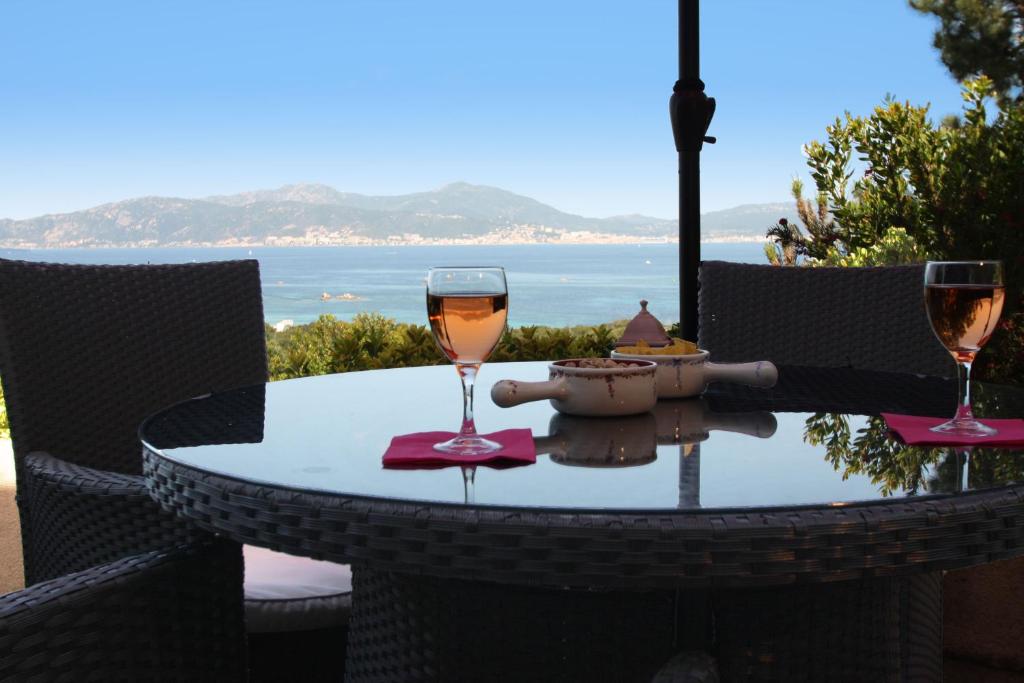 two glasses of wine sitting on a table with a view of the ocean at Villa Ghiatone in Pietrosella
