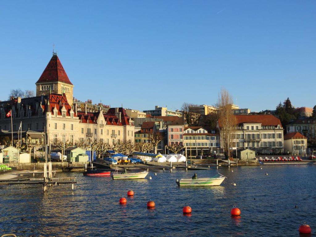 a group of boats in a body of water with buildings at Hôtel du Port in Lausanne