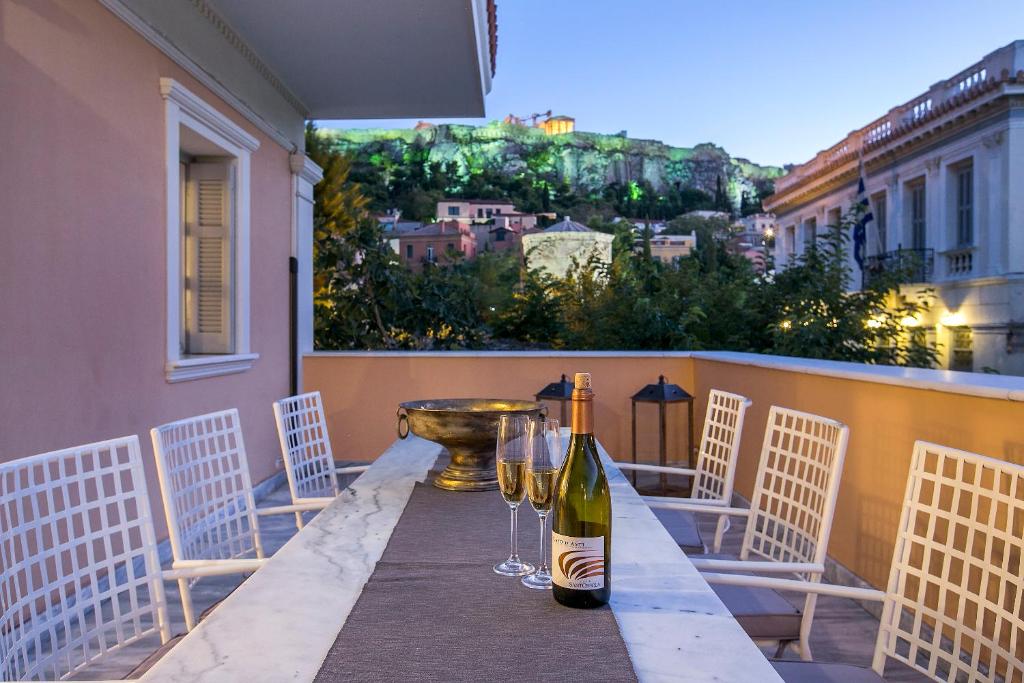 a table with two wine bottles and glasses on a balcony at Aerides Luxury Suites in Athens