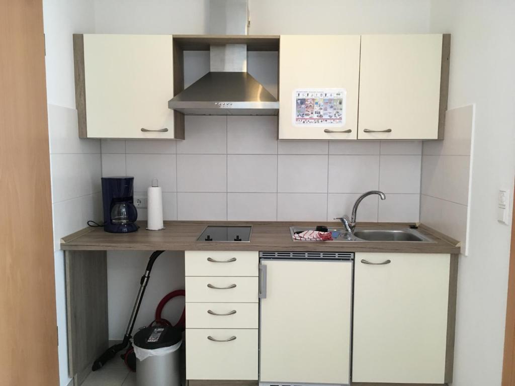małą kuchnię z białymi szafkami i zlewem w obiekcie Boardinghouse Casita Amann w mieście Friedrichshafen